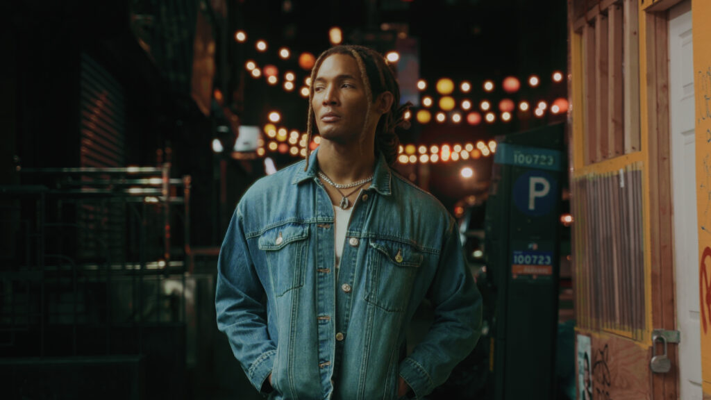 Color grading example from a profesional film colorist. Black man in jean jacket outside at night illuminated by warm lights.